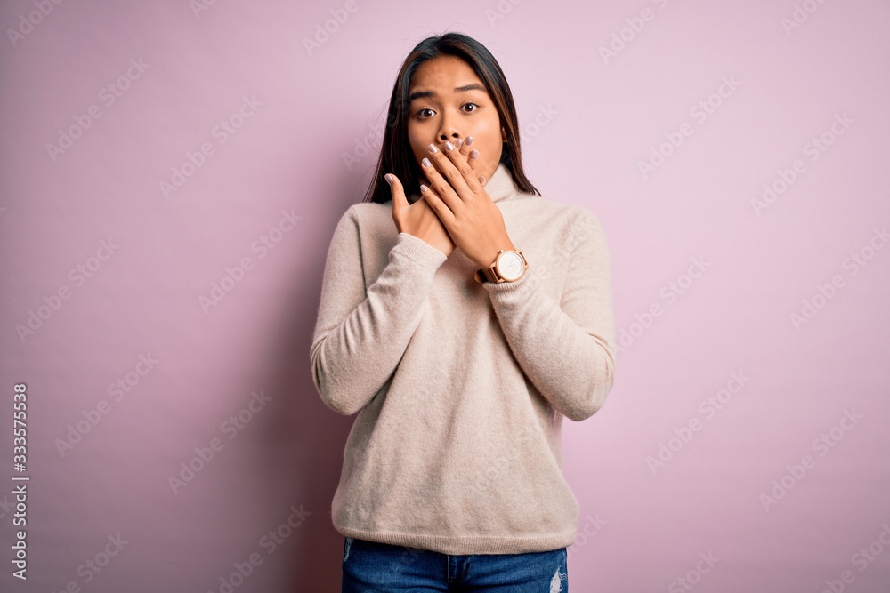Young beautiful asian girl wearing casual turtleneck sweater over isolated pink background shocked covering mouth with hands for mistake. Secret concept. Young beautiful asian girl wearing casual turtleneck sweater over isolated pink background shocked covering mouth with hands for mistake. Secret concept.