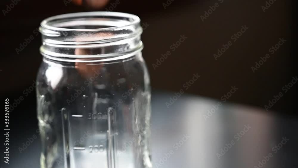 Slow motion of dropping coins into a glass jar Slow motion of dropping coins into a glass jar
