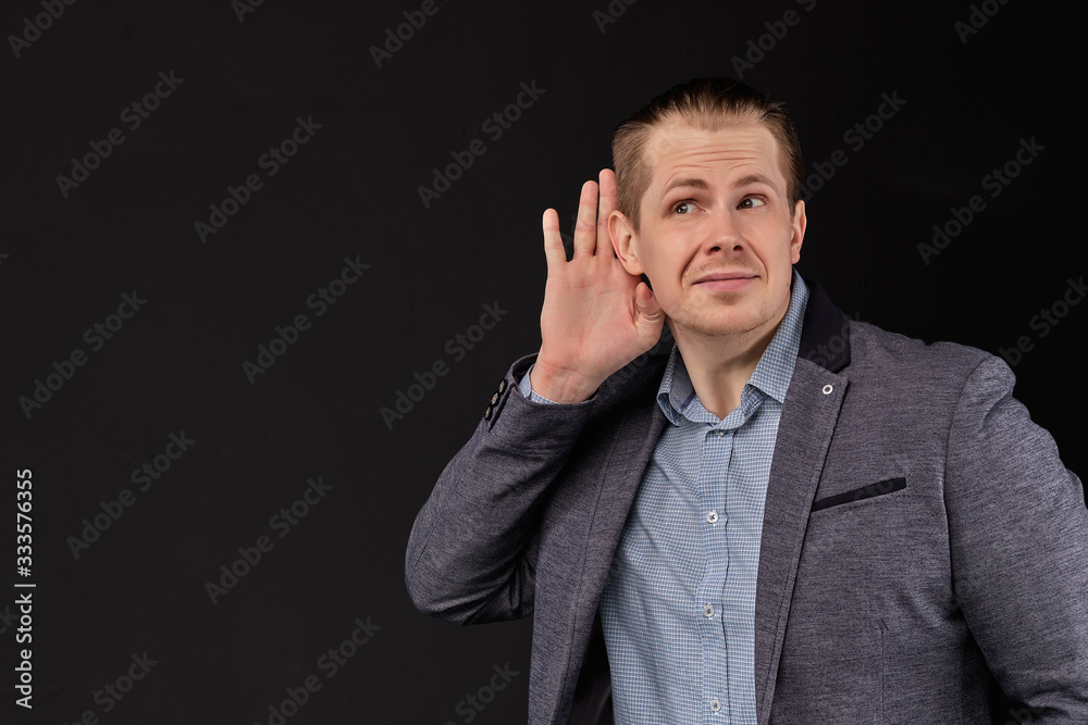 A man in a jacket hears important information on a black background. A man in a jacket hears important information on a black background.