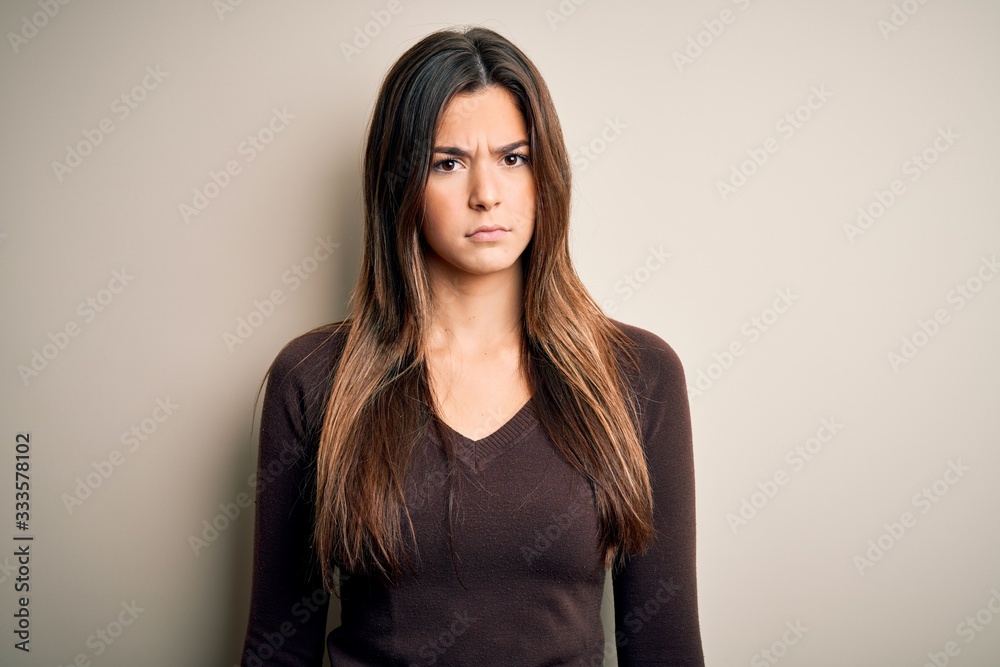 Young beautiful girl wearing casual sweater standing over isolated white background skeptic and nervous, frowning upset because of problem. Negative person. Young beautiful girl wearing casual sweater standing over isolated white background skeptic and nervous, frowning upset because of problem. Negative person.