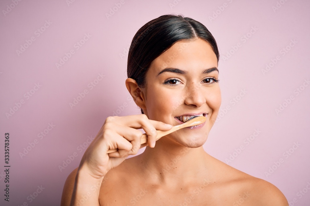 Young beautiful brunette woman brushing her teeth using tooth brush and oral paste, cleaning teeth and tongue as healthy health care morning routine Young beautiful brunette woman brushing her teeth using tooth brush and oral paste, cleaning teeth and tongue as healthy health care morning routine