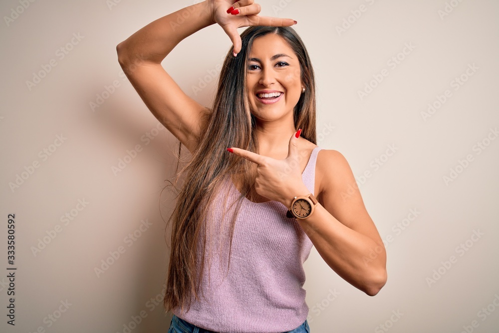 Young beautiful brunette woman with long hair standing over isolated background smiling making frame with hands and fingers with happy face. Creativity and photography concept.