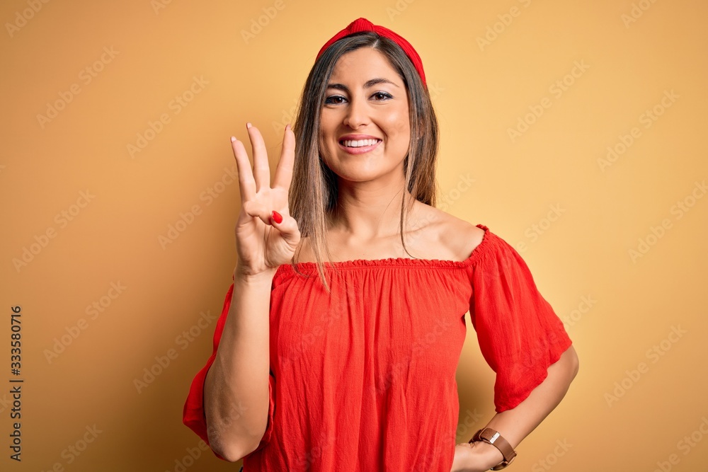 Young beautiful woman colorful summer style over yellow isolated background showing and pointing up with fingers number three while smiling confident and happy. Young beautiful woman colorful summer style over yellow isolated background showing and pointing up with fingers number three while smiling confident and happy.