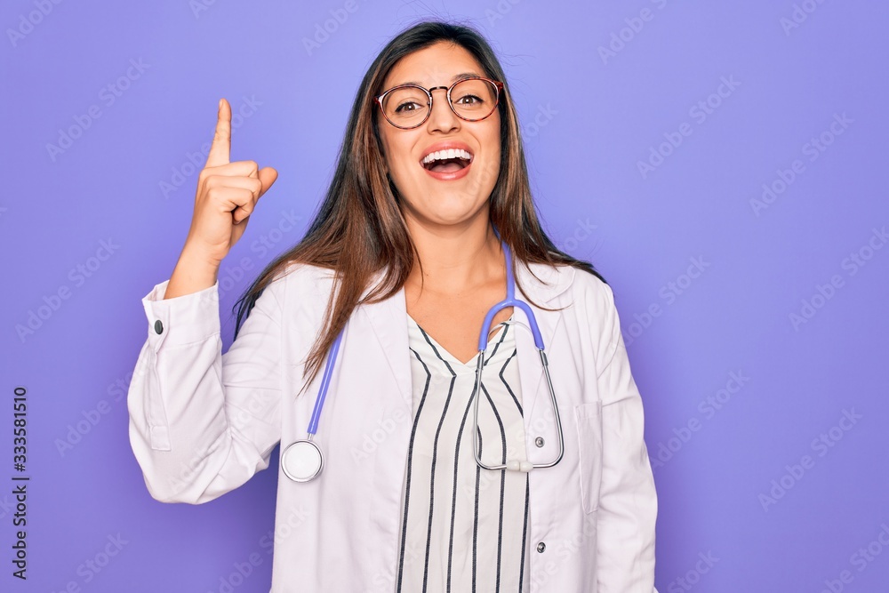 Professional doctor woman wearing stethoscope and medical coat over purple background pointing finger up with successful idea. Exited and happy. Number one. Professional doctor woman wearing stethoscope and medical coat over purple background pointing finger up with successful idea. Exited and happy. Number one.