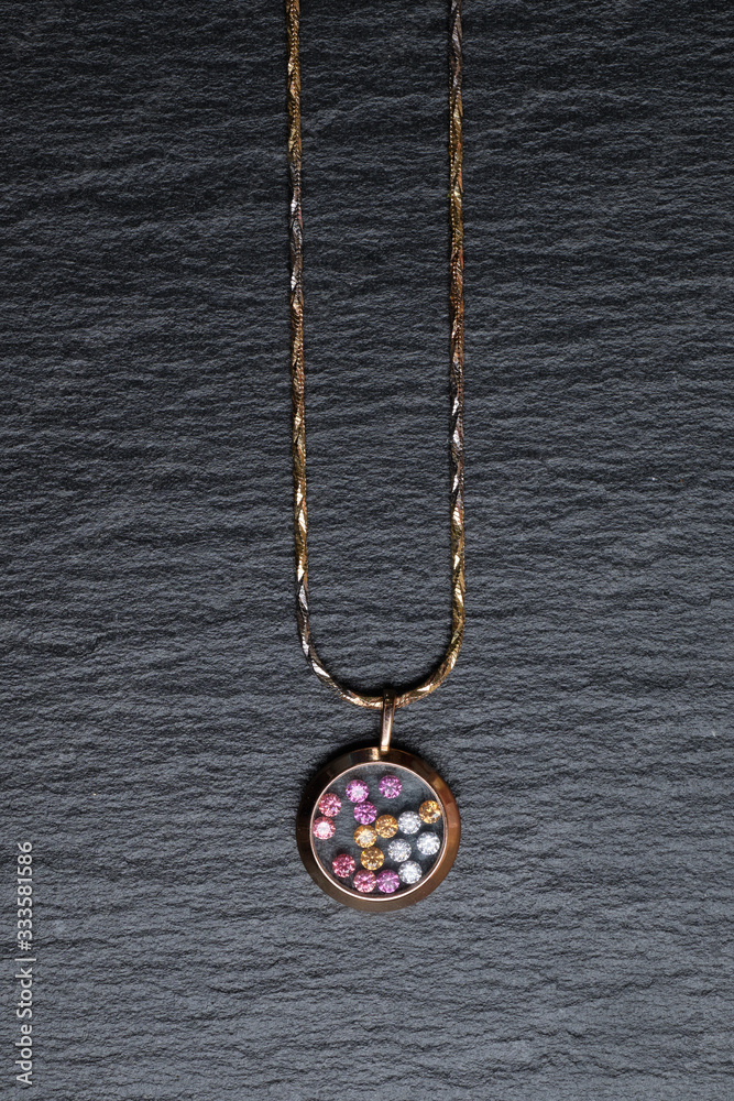 Pendant with colored rhinestones on a black stone table. Vertical. Top view. Pendant with colored rhinestones on a black stone table. Vertical. Top view.