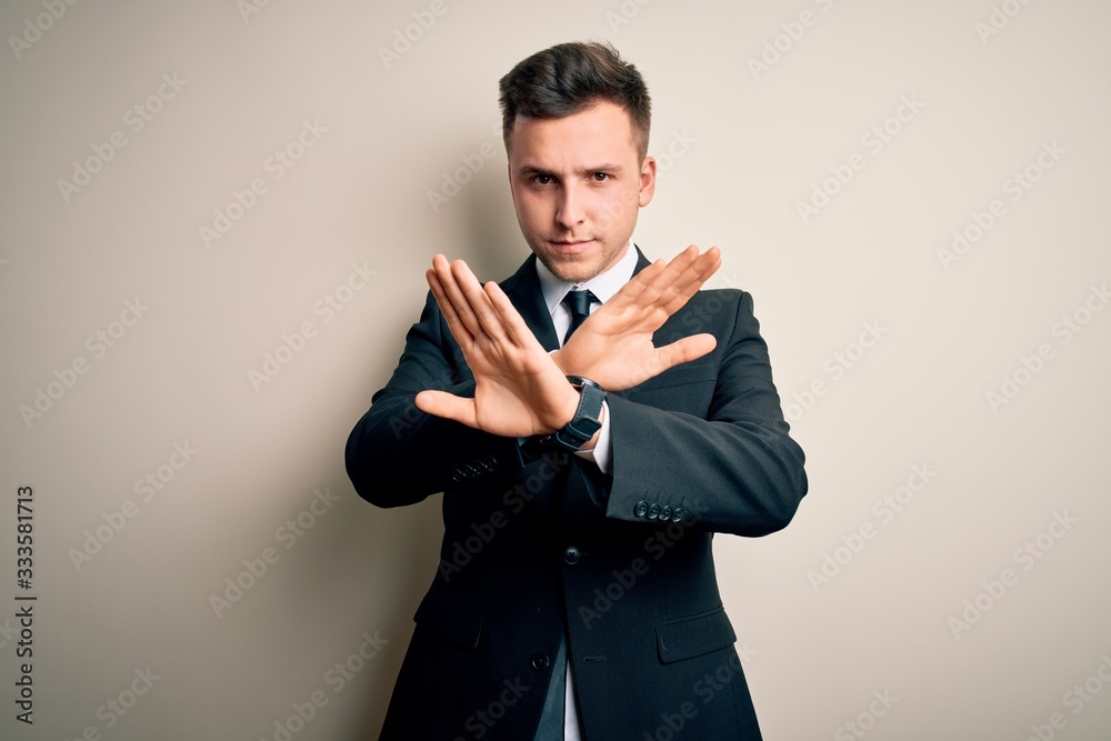 Young handsome business man wearing elegant suit and tie over isolated background Rejection expression crossing arms doing negative sign, angry face Young handsome business man wearing elegant suit and tie over isolated background Rejection expression crossing arms doing negative sign, angry face