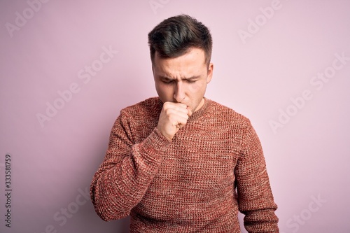 Young handsome caucasian man wearing casual winter sweater over pink isolated background feeling unwell and coughing as symptom for cold or bronchitis. Health care concept. © Krakenimages.com