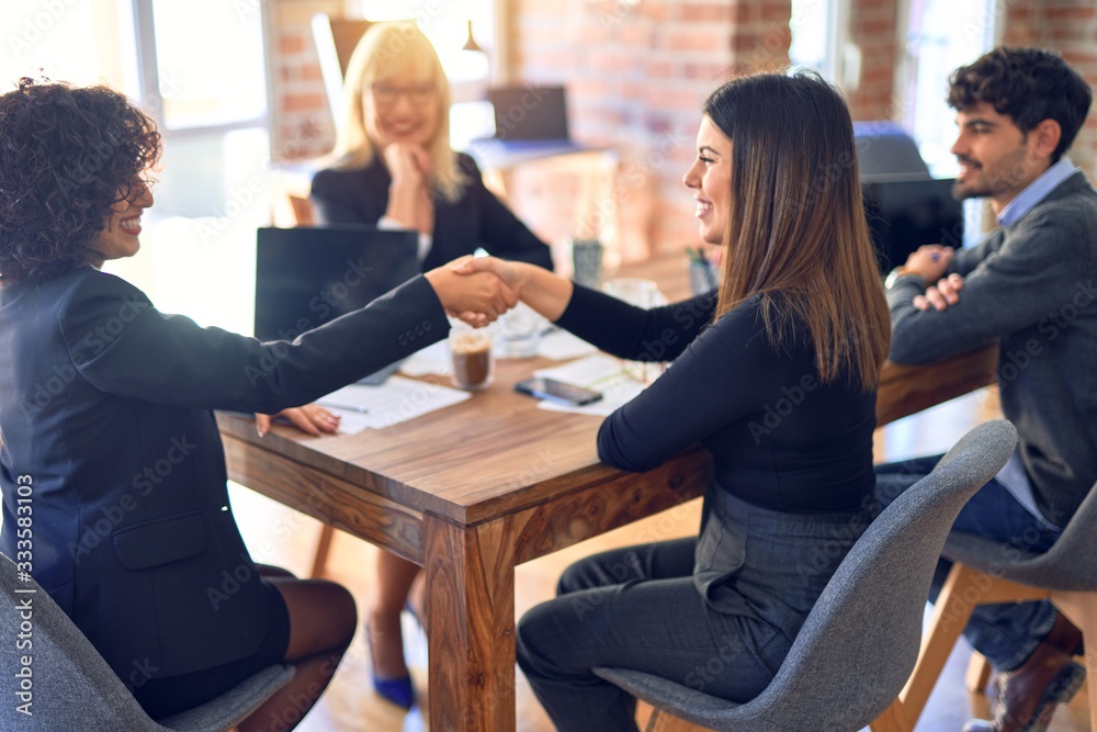 Group of business workers smiling happy and confident. Working together with smile on face shaking hands for agreement at the office Group of business workers smiling happy and confident. Working together with smile on face shaking hands for agreement at the office