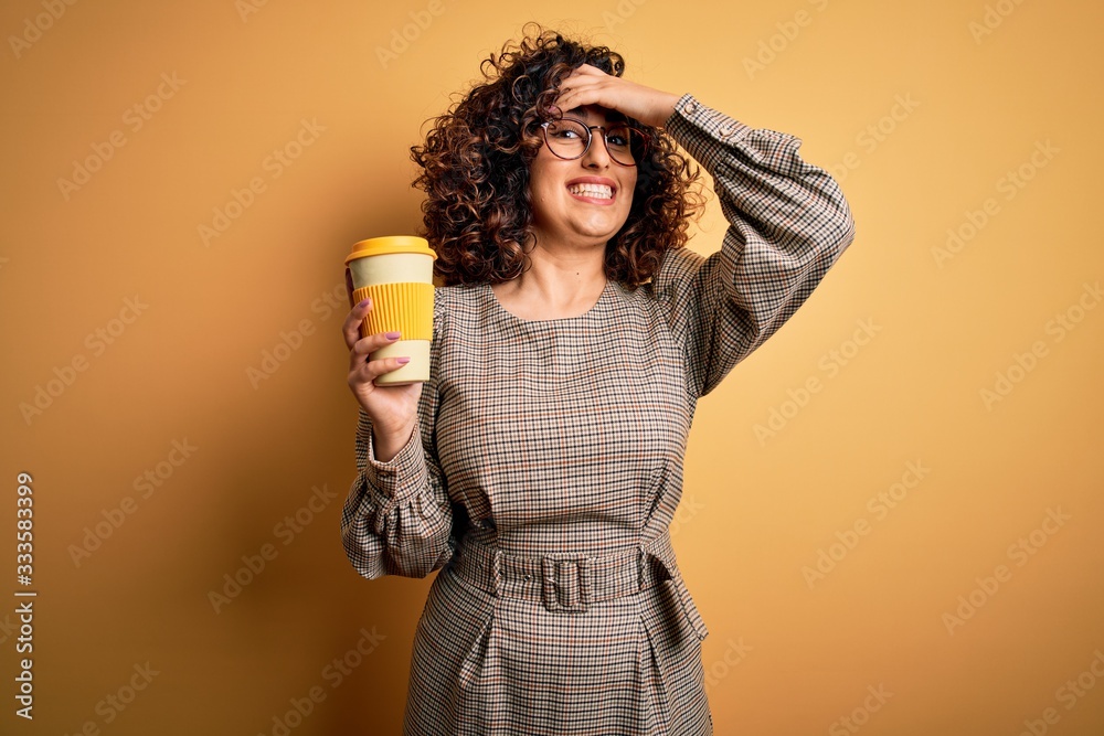 Young beautiful curly arab businesswoman wearing glasses drinking cup of takeaway coffe stressed with hand on head, shocked with shame and surprise face, angry and frustrated. Fear and upset for Young beautiful curly arab businesswoman wearing glasses drinking cup of takeaway coffe stressed with hand on head, shocked with shame and surprise face, angry and frustrated. Fear and upset for
