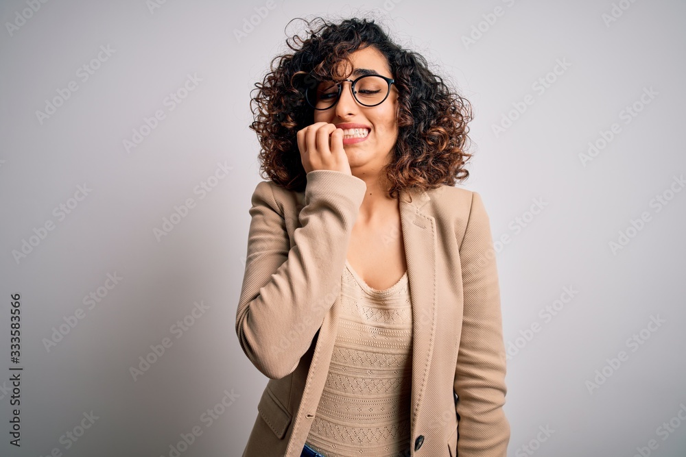 Young curly arab business woman wearing elegant jacket and glasses over white background looking stressed and nervous with hands on mouth biting nails. Anxiety problem. Young curly arab business woman wearing elegant jacket and glasses over white background looking stressed and nervous with hands on mouth biting nails. Anxiety problem.