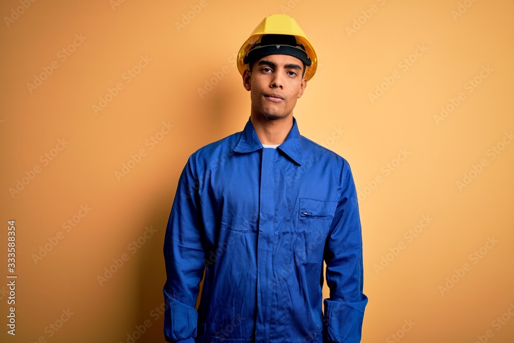 Young handsome african american worker man wearing blue uniform and security helmet looking sleepy and tired, exhausted for fatigue and hangover, lazy eyes in the morning.