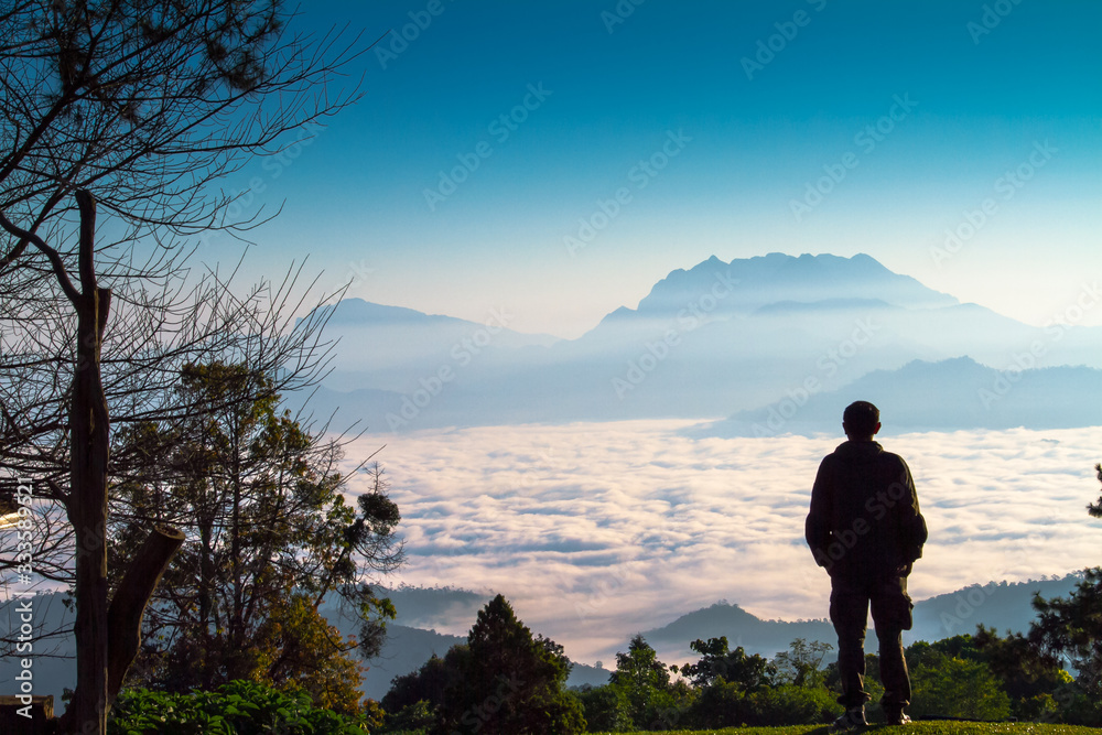 man on the top of mountain with sea of mist in background