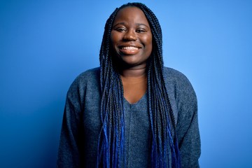 African american plus size woman with braids wearing casual sweater over blue background with a happy and cool smile on face. Lucky person.