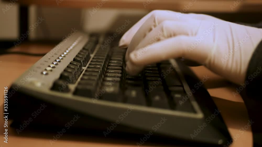 Man with medical gloves typing on a keyboard to protect against virus Covid-19 Man with medical gloves typing on a keyboard to protect against virus Covid-19