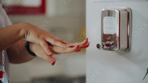Detail of a female hand sanitizing her hands with gel alcohol in the workplace photo