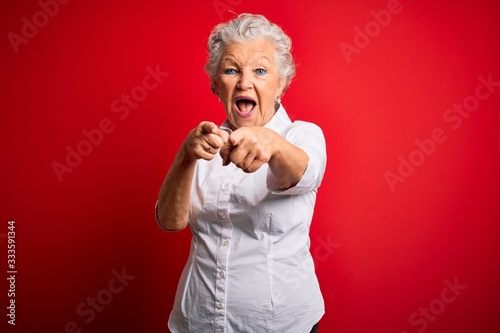Senior beautiful woman wearing elegant shirt standing over isolated red background pointing to you and the camera with fingers, smiling positive and cheerful