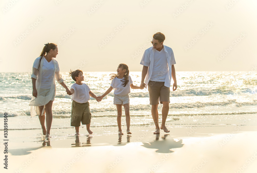 Smiling Young Asian happy family parents with child walking and holding hands together on the beach in summertime. Father, mother and kids relax and having fun summer lifestyle travel holiday vacation