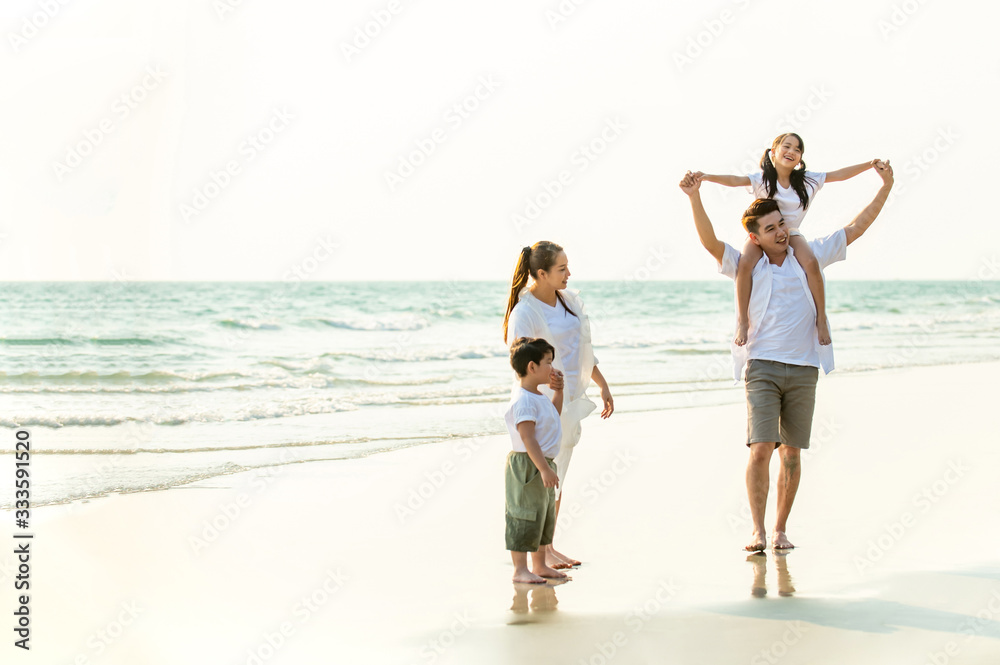 Happy Young Asian happy family parents with child walking and having fun together on the beach at sunset in summertime. Father, mother and kids relax and enjoy summer lifestyle travel holiday vacation