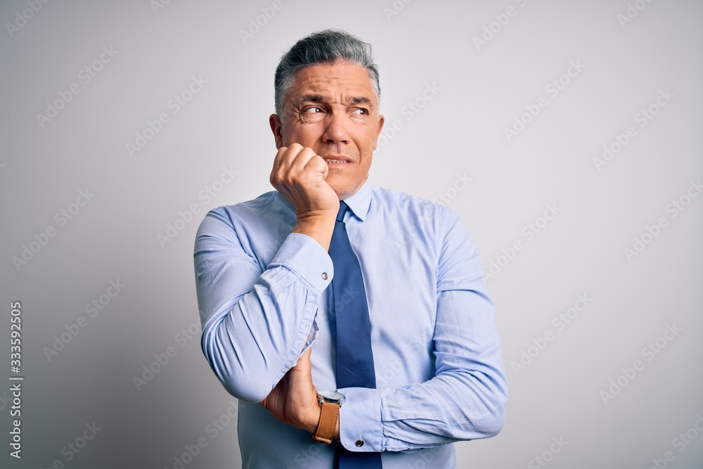 Middle age handsome grey-haired business man wearing elegant shirt and tie looking stressed and nervous with hands on mouth biting nails. Anxiety problem. Middle age handsome grey-haired business man wearing elegant shirt and tie looking stressed and nervous with hands on mouth biting nails. Anxiety problem.