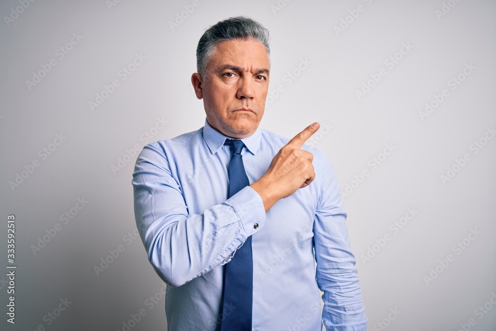 Middle age handsome grey-haired business man wearing elegant shirt and tie Pointing with hand finger to the side showing advertisement, serious and calm face Middle age handsome grey-haired business man wearing elegant shirt and tie Pointing with hand finger to the side showing advertisement, serious and calm face