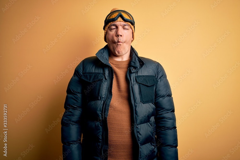 Middle age handsome grey-haired skier man on vacation wearing ski goggles making fish face with lips, crazy and comical gesture. Funny expression. Middle age handsome grey-haired skier man on vacation wearing ski goggles making fish face with lips, crazy and comical gesture. Funny expression.