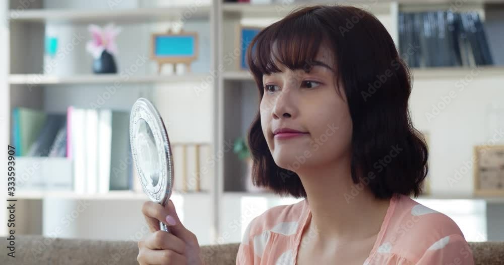 Happy smiling asian young woman looking at mirror Happy smiling asian young woman looking at mirror