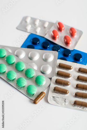 Colorful pills and capsules in blister packs on a white background. Coronavirus. Pharmaceutical industry. Antibiotics