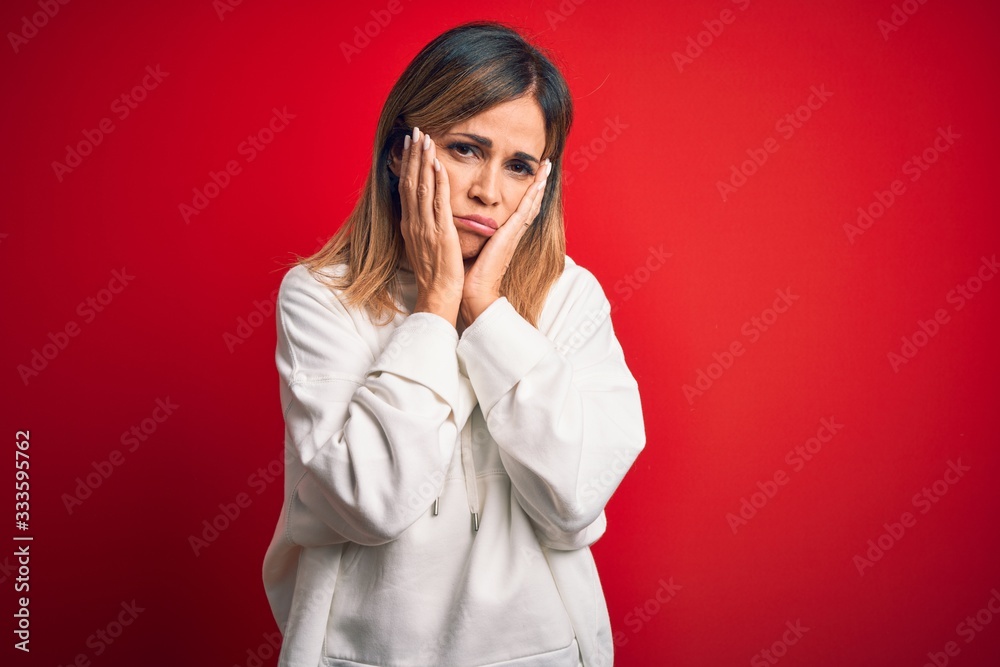 Middle age beautiful sportswoman wearing casual sweatshirt over isolated red background Tired hands covering face, depression and sadness, upset and irritated for problem Middle age beautiful sportswoman wearing casual sweatshirt over isolated red background Tired hands covering face, depression and sadness, upset and irritated for problem