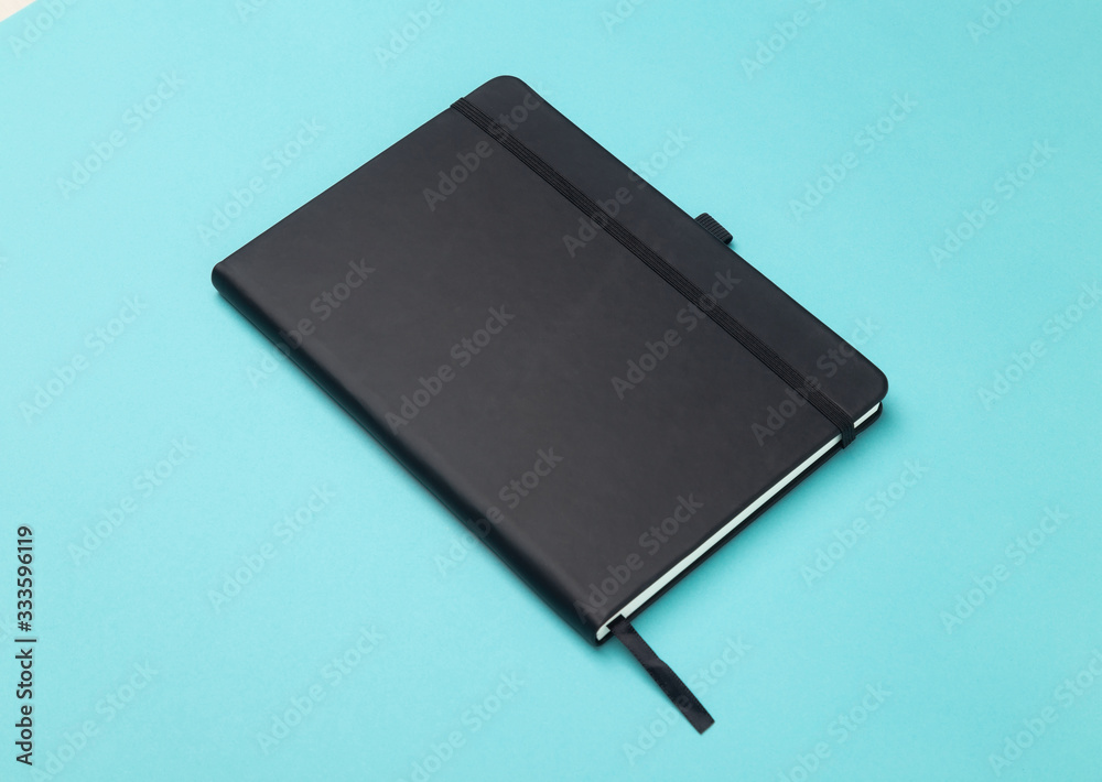 Black notebook isolated on blue background. Black notebook isolated on blue background.