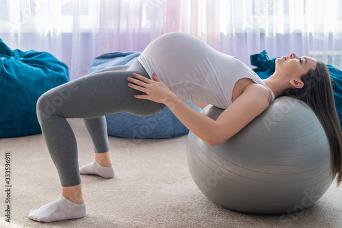 Beautiful european woman doing pregnant exercises. Expectant mother is doing exercises with a fitness sword. Yoga for expectant mothers.