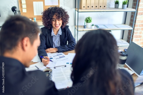 Young beautiful couple applying for mortgage. Sitting smiling happy meeting with real state agent signing mortgage loan at bank