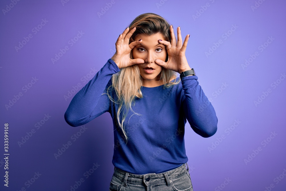 Young beautiful blonde woman wearing casual t-shirt over isolated purple background Trying to open eyes with fingers, sleepy and tired for morning fatigue Young beautiful blonde woman wearing casual t-shirt over isolated purple background Trying to open eyes with fingers, sleepy and tired for morning fatigue
