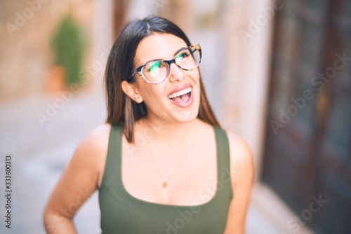 Young beautiful woman smiling happy and confident. Standing with smile on face at the town street