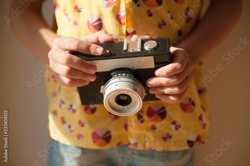 home hobby leisure concept photograph of little kid in yellow shirt holding vintage film camera