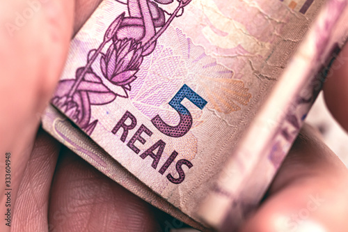 Brazilian Real, money from Brazil. Man holding a banknote of five reais. photo