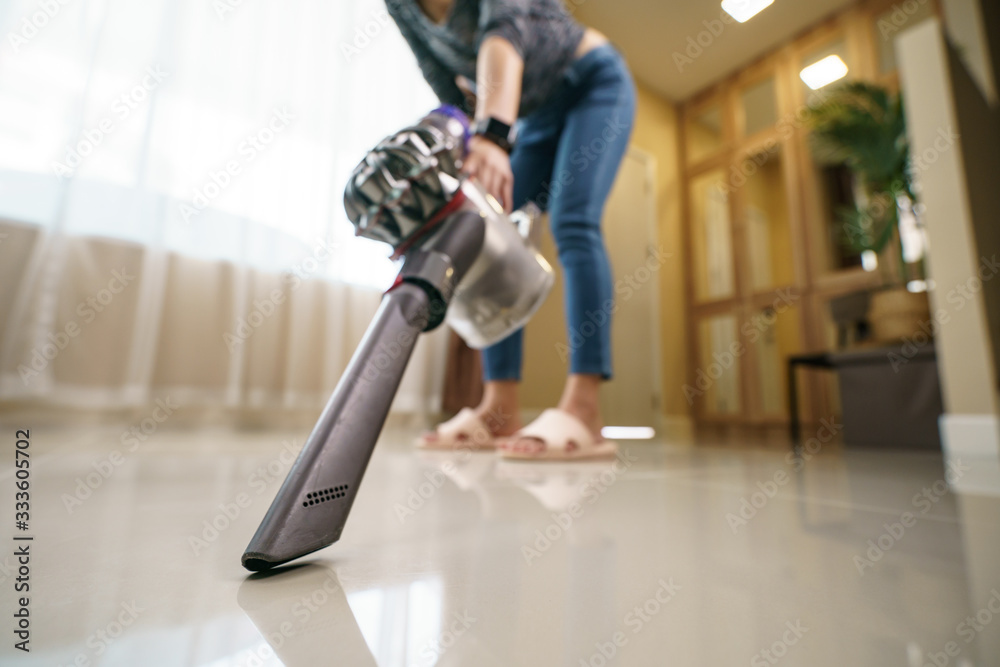 Woman use vacuum cleaner cleaning on floor.