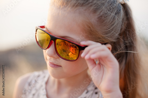 beautiful small girl look at her little kid brother through summer sunglasses with love and care