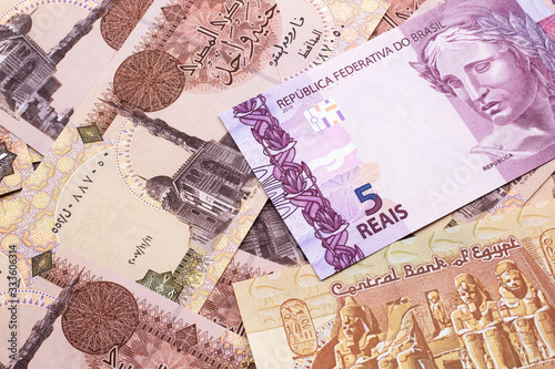 A pink five reais bank note from Brazil close up in macro with a background of Egyptian pound bills