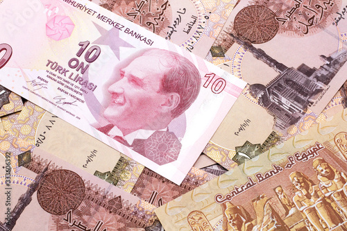 A close up image of a red ten Turkish lira bank note on a background of Egyptian one pound bank notes in macro