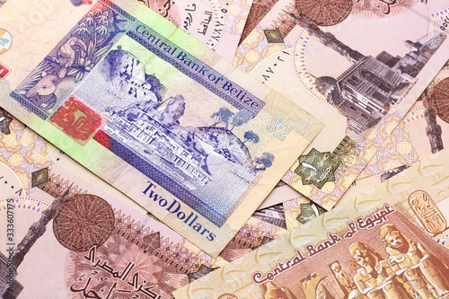 A close up image of a colorful two dollar bill from Belize with a pile of Egyptian one pound bank notes in macro