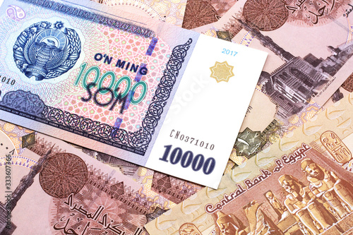 A close up image of a ten thousand Uzbek som bank note on a background of brown, Egyptian one pound bank notes bills in macro