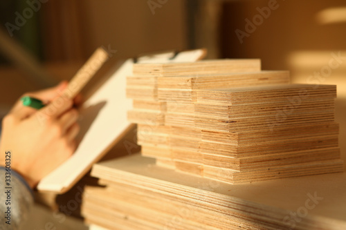 Wooden bars lying in a row closeup with manual worker in background. DIY job, inspiration, improvement, fix shop, powersaw bench, joinery startup, workplace idea, career, ruler, industrial education