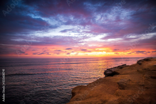 Tableau sur toile The sky erupts in vibrant colors, as the sun sets over the Pacific Ocean, at Sunset Cliffs in San Diego, California