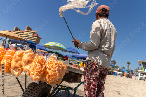 Street vendor on beach selling food holding a streamer in the wind photo