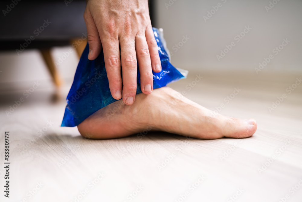 Fototapeta premium Man Applying Ice Gel Pack On His Ankle