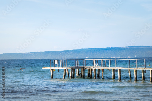 Rustic wood pier and buoy around at sea with hill background. The pier is at beach in Guzelyali Plaji, Canakkale,  Turkey photo