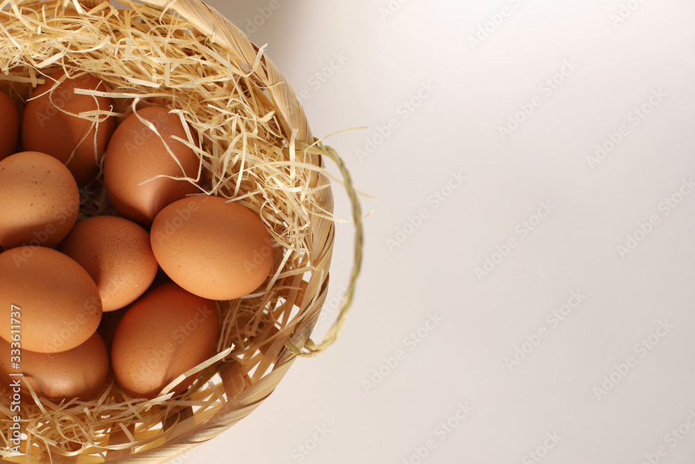 Easter basket on its side. Brown eggs in a basket on a straw. A wicker basket filled with chicken eggs. Easter basket on its side. Brown eggs in a basket on a straw. A wicker basket filled with chicken eggs.