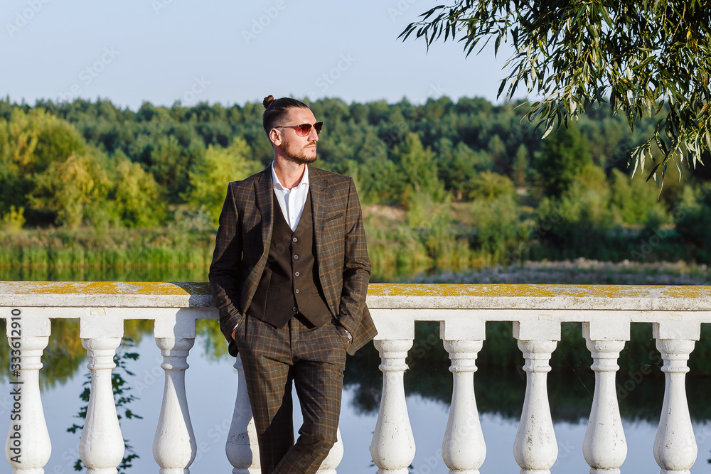 Obraz premium Fashionable guy in a suit and sunglasses on the pier