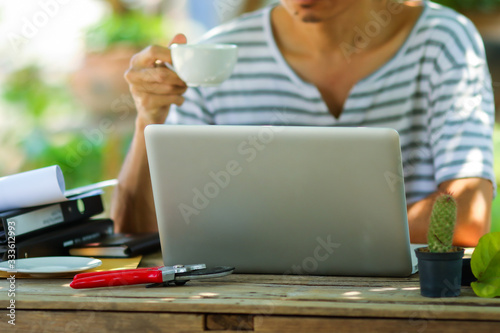 Young asian man working online from home at the garden. Man using laptop for online working at home.
