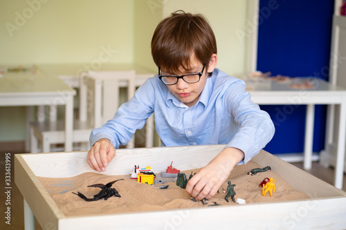 boy glasses is sand therapy on table with light